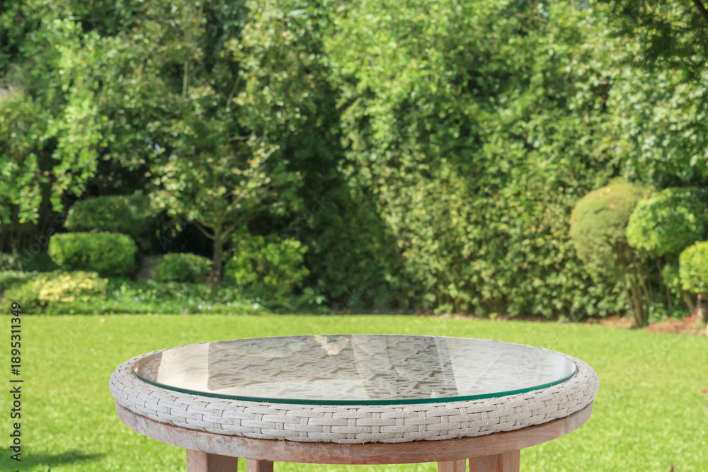 Fototapeta premium Empty round glass table top with abstract blur green park garden background