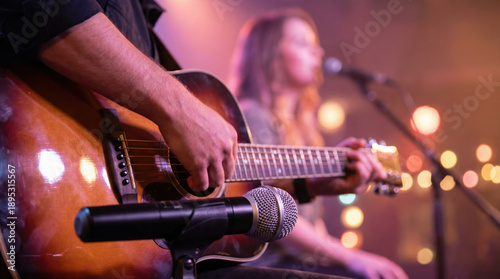 Musician playing guitar on stage with a microphone during a live music concert performance