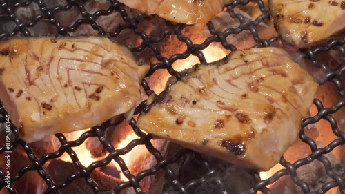 close up salmon BBQ grill with metal tools to turn the salmon during cooking 4kFresh fish is placed on a grill, cooking over hot flames. The grill marks create a savory look as the fish cooks. 