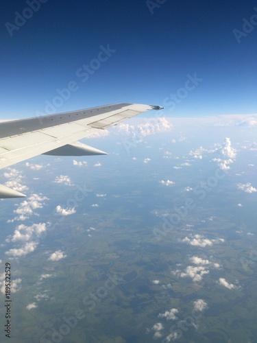 Aerial view from Sukhoi Superjet 100 window flying over Russia, airplane wing above clouds, international flight passenger perspective. June 2013.