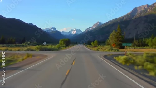 Endless road leads through a scenic mountain valley under a clear blue sky.