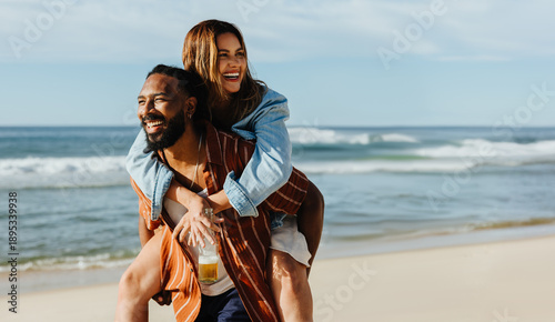 Εκτύπωση καμβά Couple enjoying a piggyback ride together on a sunny day at the beach