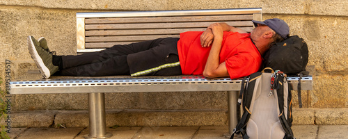 Foto Man sleeping on a bench in a historic town