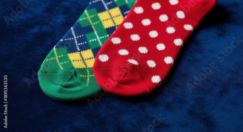 Two colorful socks on blue background green plaid and red polka dots