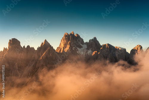 фотографія Sunrise shining on Cadini di Misurina peaks and foggy in Dolomites, Italy