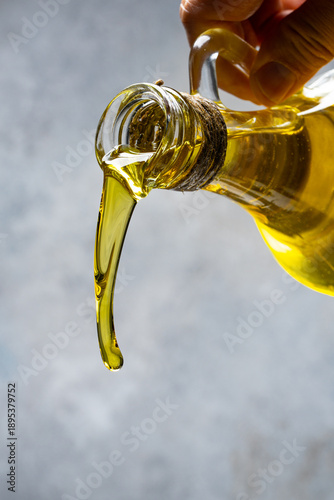 Photos Organic olive oil pouring from carafe on vintage stone background
