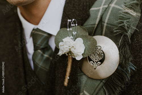 Foto Close up of Scottish groom's flower buttonhole with tartan fly plaid over should