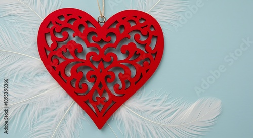 Red heart shaped wooden decoration with intricate cutouts and white feathers