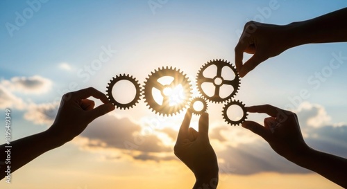 Hands holding gears against a vibrant sunset sky