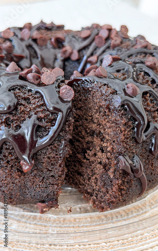 Rich chocolate bundt cake with chocolate chips and ganache topping on glass plate for bakery dessert menus - concept of café, bakery, pastry shop