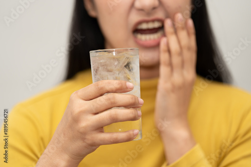 Woman feeling tooth pain while holding a glass of cold water, sensitive teeth problem, dental health issue, oral care concept, discomfort and pain expression. toothache, dental, sensitivity, teeth,
