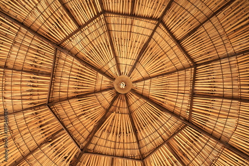 Vista inferior simétrica del interior de un techo de palapa de paja con patrón geométrico radial y textura de bambú