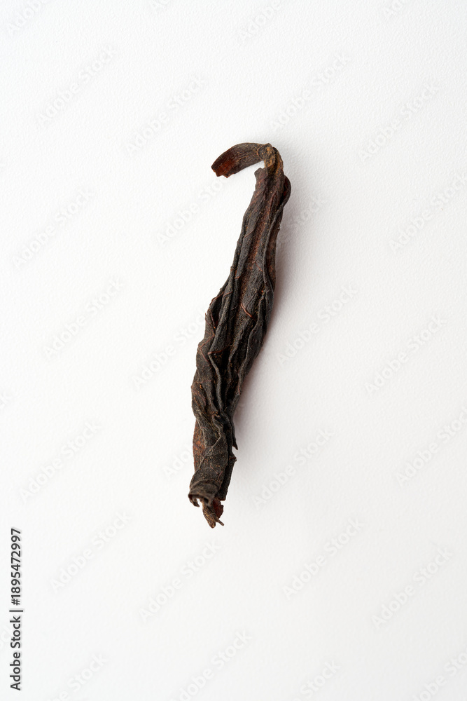 Fototapeta premium Single dried premium Chinese tea leaf sprout with golden fuzz isolated on white background. High-quality loose leaf tea macro photography.