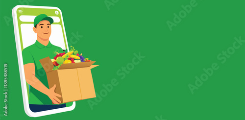 A worker in a green uniform holding a cardboard box with fresh items.