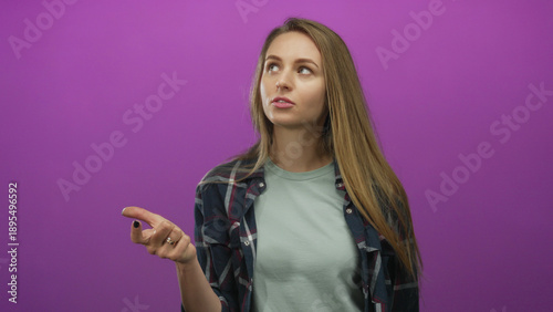 Slika na platnu Young woman counting with fingers against pink background appearing focused expr