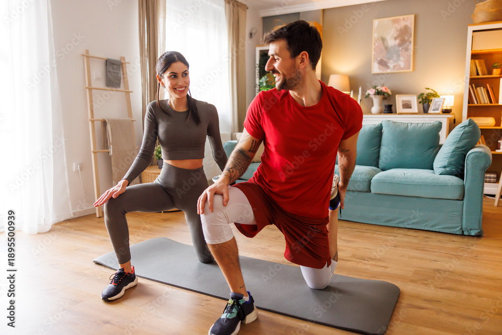 Obraz premium Couple stretching legs while working out at home