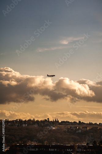 Commercial airplane flying above thick clouds at sunset sky