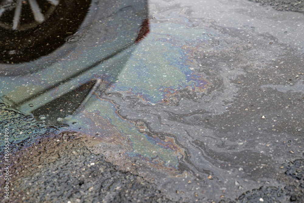 Naklejka premium Oil sheen rainbow pattern floating on puddle on asphalt road