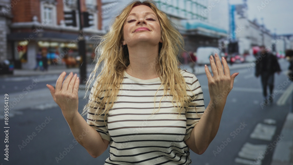 Fototapeta premium Woman holding palms up in open gesture on a busy city street with striped shirt visible; playful curiosity.