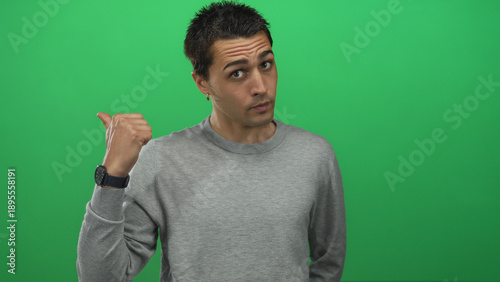 Bilde på lerret Young hispanic man points finger at camera in studio before green wall with stern expression; rejection