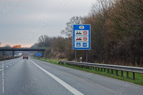 Speed limit board 50 100 130 beside autobahn bridge.