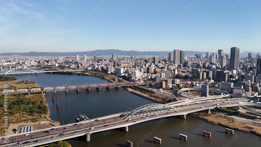 Obraz premium Osaka City, Japan: Aerial Drone View of CBD, Skyscrapers, Urban Cityscape, Yodogawa Riverside Park, Yodo River, Osaka Skylines, Shin-Yodogawa Bridge, Railway Bridges in Yodogawa Ward, Kita Ward