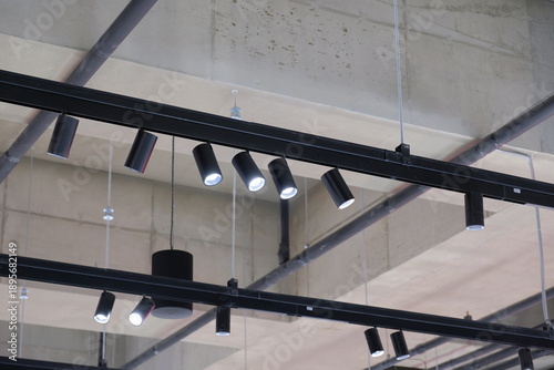 Modern track lighting system with adjustable spotlights mounted on black rails against a concrete ceiling