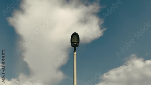 Slow zoom-in of a Solar-powered street light against a blue sky with fluffy white clouds, Seletar, Singapore.