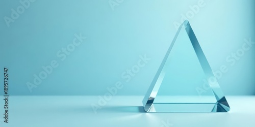 A translucent triangular prism rests on a pale blue surface, a minimalist study in light and form