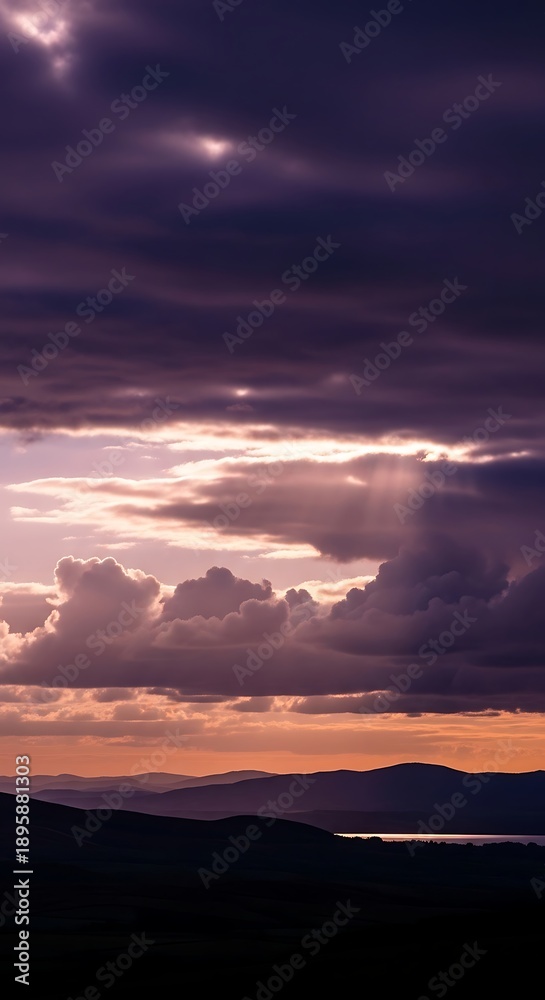 Fototapeta premium Dramatic sunset over mountains and water with cloudy sky