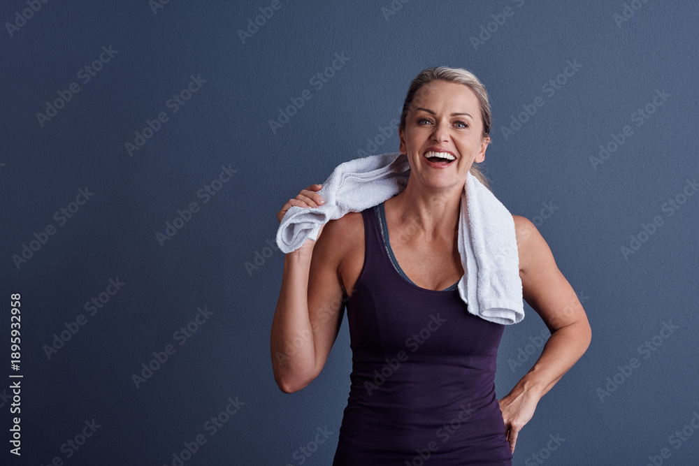 Fototapeta premium Fitness, towel and laughing with portrait of woman in studio for health, workout rest and funny joke. Happiness, wellness and training break with mature person on background for mockup space