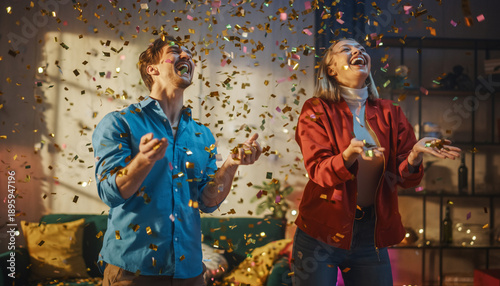 Two people celebrating with confetti in a cozy living room, capturing a joyful moment from a slightly angled viewpoint