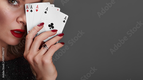 Four Aces Held By Woman Glamorous Closeup Red Lips Red Nails Diamond Ring Sequined Dress Confident Gaze Professional Poker Player Pose High Stakes Poker Vibe Studio Gray Background