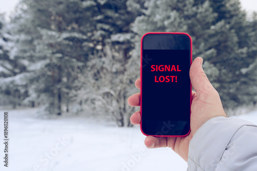 Tableau sur toile Hand holding smartphone showing SIGNAL LOST with snowy pine trees blurred in bac