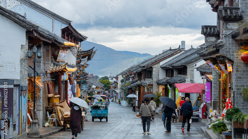 Foto People with umbrellas walking through an ancient town street with traditional Chinese architecture on a rainy day