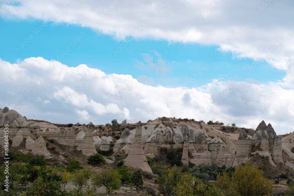 Obraz premium Wide landscape view of Love Valley Trail in Goreme, Cappadocia, Turkey Türkiye, featuring distinctive fairy chimney rock formations under a clear blue