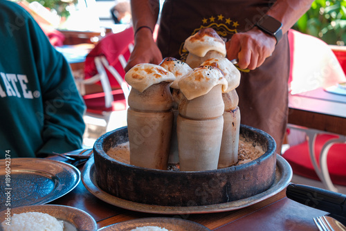 Traditional Turkish pottery kebab (Testi Kebabı) served in a clay pot and broken open at the table, revealing slow-cooked meat stew in a restaurant