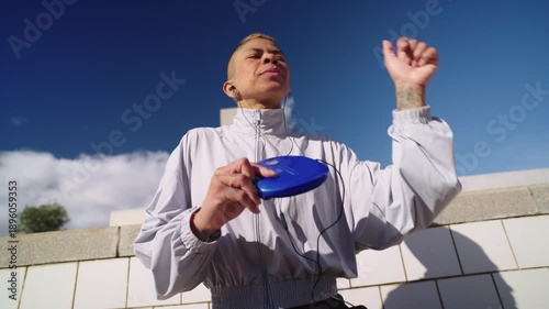 Androgynous person dancing and listening to music on a portable cd player