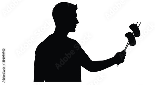 Silhouette of a man playfully holding up two shoes