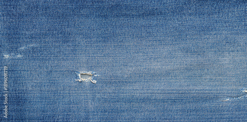 Tablou pe pânză Blue denim fabric with worn texture and small rip