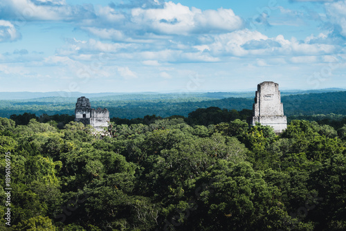 Fotografie Lost city of Tikal appearing above lush jungle vegetation, showcasing the grande
