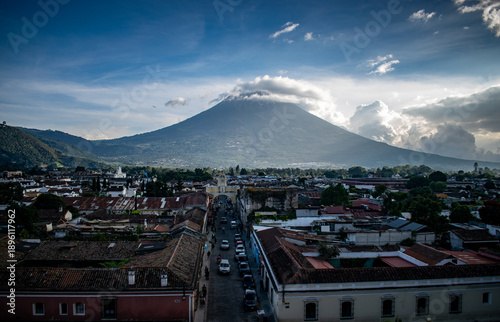 Panoramic view over the colonial city of Antigua with the majestic Volcán de Agua rising dramatically in the background under a vibrant Guatemalan sky