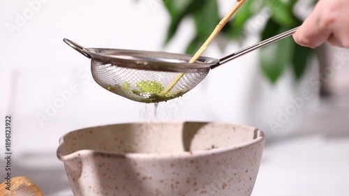 The process of preparing matcha, straining and sifting matcha through a sieve