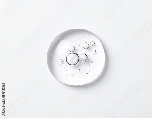 Clear droplet with trapped air bubbles on a white surface