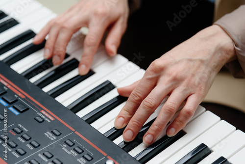 female pianist hands on black and white synthesizer keyboard, close-up view, young woman playing piano, professional musician