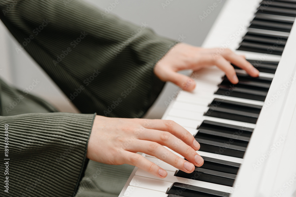 Fototapeta premium female pianist hands on black and white synthesizer keyboard, close-up view, young woman playing piano, professional musician