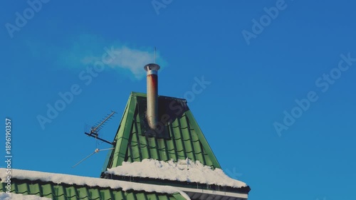 Close-up winter view of a residential house metal roof with a ventilation pipe emi