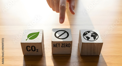 Hand pointing to wooden blocks with eco symbols representing CO2, Net Zero, and planet Earth, symbolizing environmental protection and sustainability