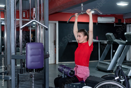 Woman in a wheelchair lifting weight in gym