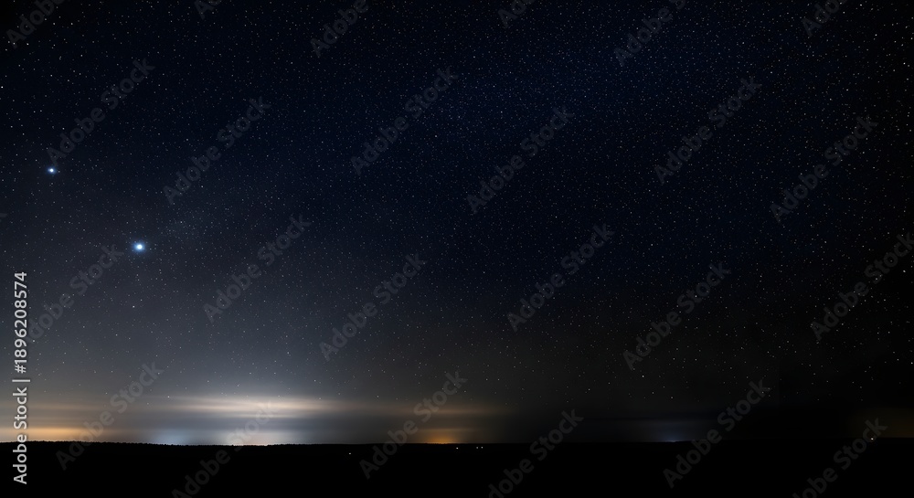Obraz premium Distant Lights Reflect on Water Under a Starry Night Sky.